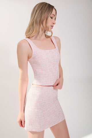 The model is wearing a pink rose Tweed Tank Top and Jenny Tweed Mini Skirt by Chloe Colette showing the front side view.