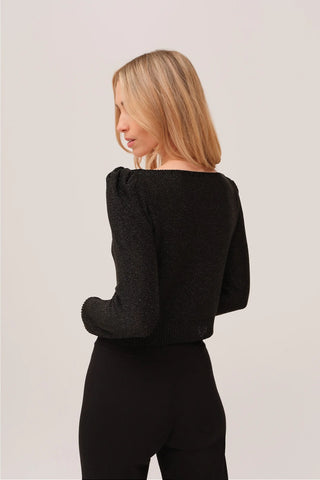 The model is wearing a black quartz Jolie Lite-knit sweater by Chloe Colete with black jogging pants showing the back side view.