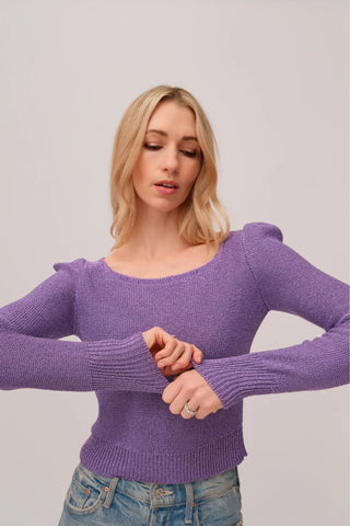 The model is wearing a purple topaz Jolie Lite-knit sweater by Chloe Colete with blue jeans.