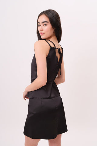 The model is wearing a black tourmaline Mykonos Satin Top and Jenny Mini Skirt by Chloe Colette.