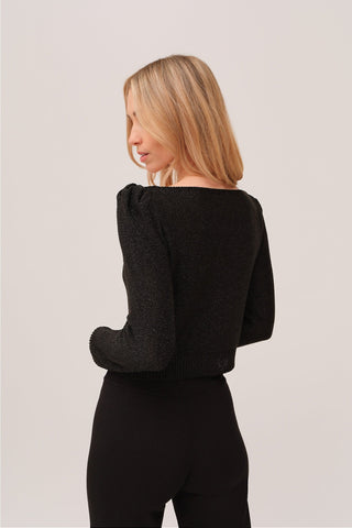 The model is wearing a black quartz Jolie Lite knit by Chloe Colete with black Malibu jogging pants showing the back side view.