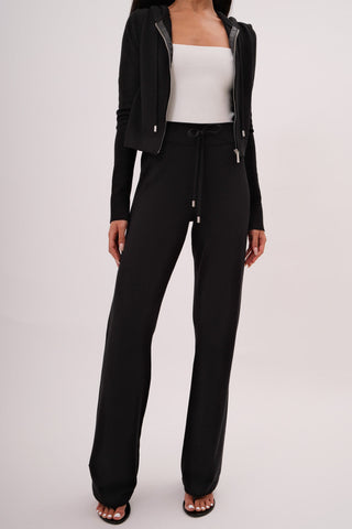 The model is wearing a black noir Malibu Zip Up Hoodie and Women's Cord Pants by Chloe Colette.