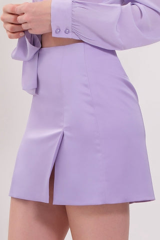 The model is wearing a light lavennder satin Jenny Mini Skirt by Chloe Colette showing close up side view.