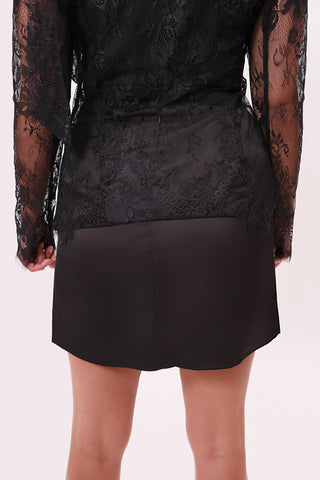 The model is wearing a black satin Jenny Mini Skirt by Chloe Colette showing the back side.