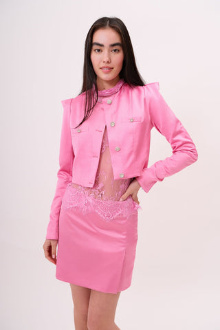 The model is wearing a satin pink rose Jacket and Jenny Mini Skirt by Chloe Colette showing the front side.