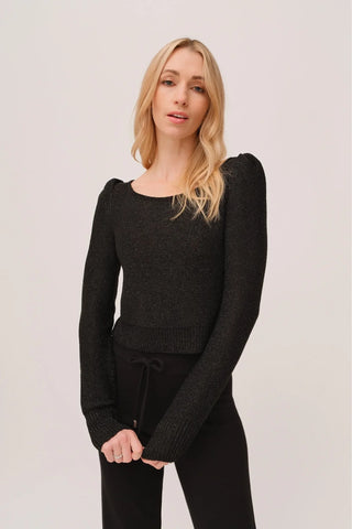 The model is wearing a black quartz Jolie Lite-knit sweater by Chloe Colete with black jogging pants.