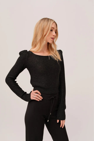 The model is wearing a black quartz Jolie Lite knit by Chloe Colete with black jogging pants.