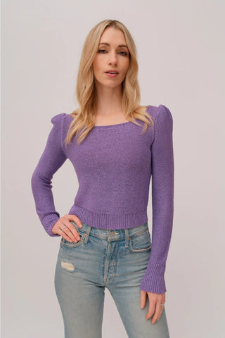 The model is wearing a purple topaz Jolie Lite knit by Chloe Colete with blue jeans.