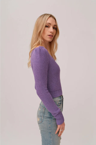 The model is wearing a purple topaz Jolie Lite-knit sweater by Chloe Colete with blue jeans.