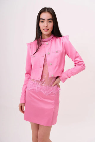 The model is wearing a satin pink pearl Juliette Jacket and Jenny Mini Skirt by Chloe Colette.