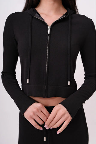 The model is wearing a black noir Malibu Zip-Up Hoodie and Cord Pants by Chloe Colette.